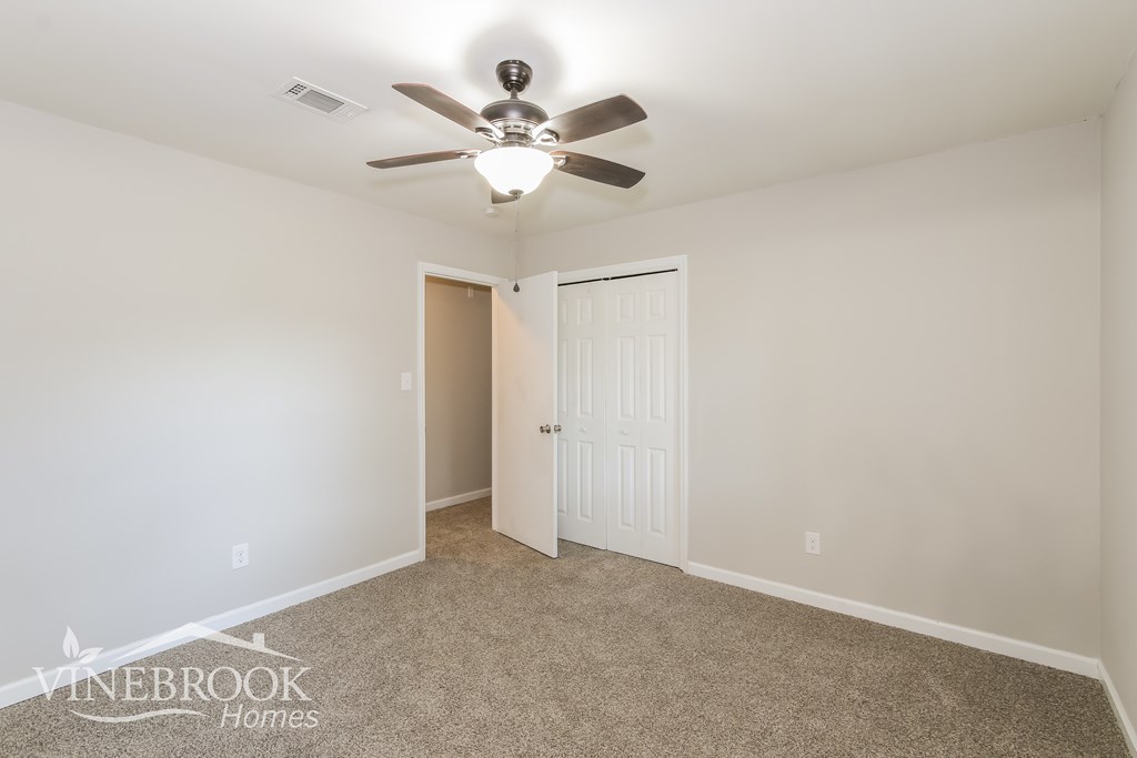 a bedroom with a ceiling fan and a door to a closet